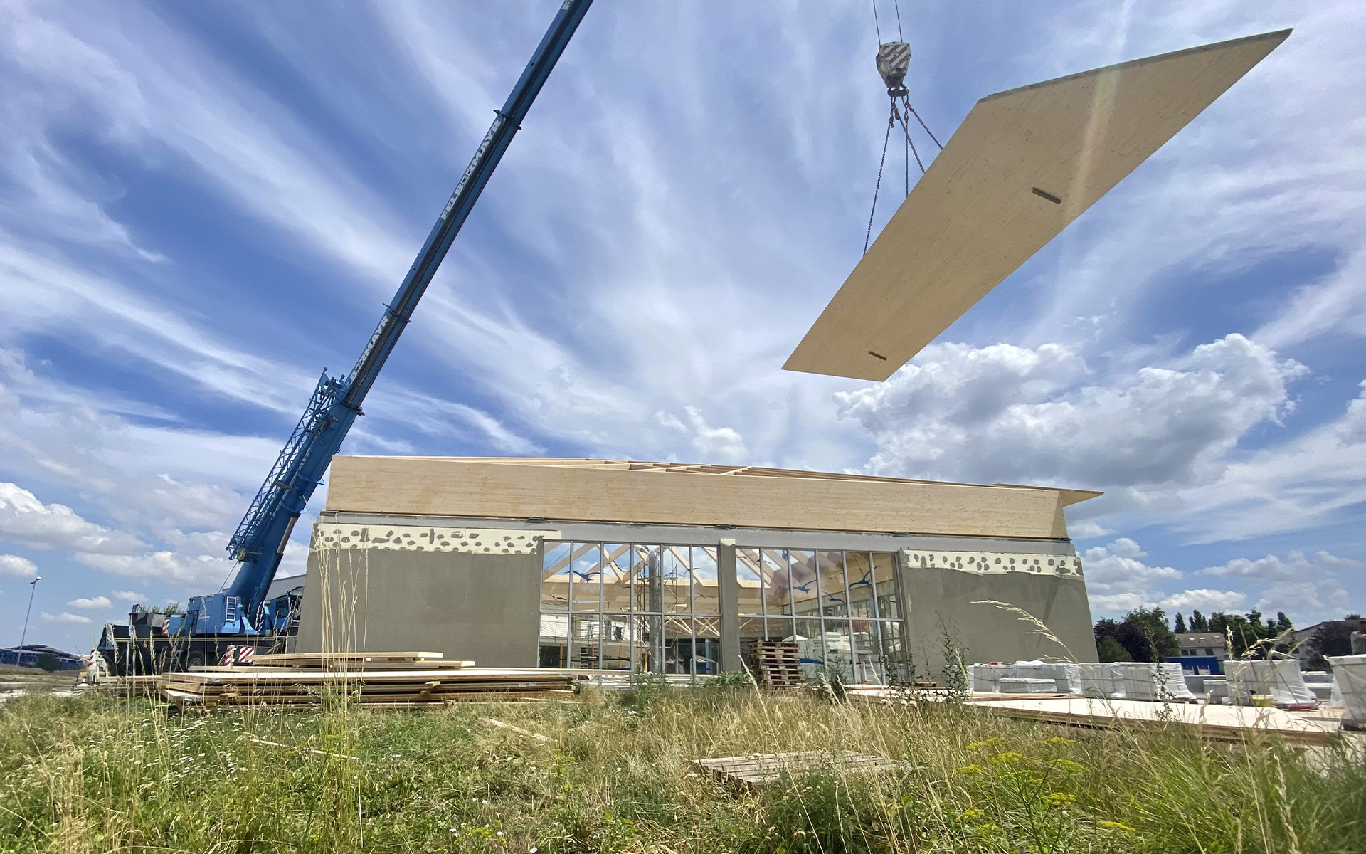 Crane lifting prefabricated timber roof panel on construction site using lifting systems for wooden prefabricated buildings